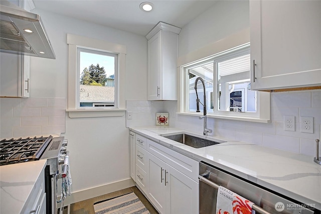 kitchen featuring under cabinet range hood, a sink, tasteful backsplash, appliances with stainless steel finishes, and white cabinetry