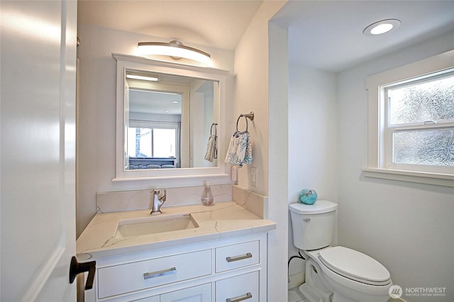 bathroom featuring a wealth of natural light, toilet, and vanity
