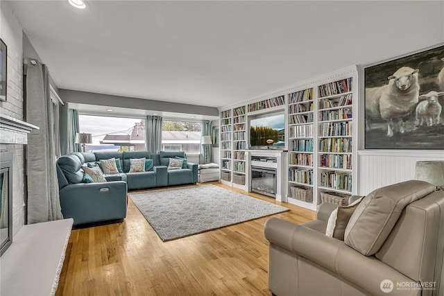 living area with a glass covered fireplace, built in features, and wood finished floors