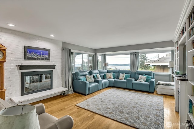 living area featuring a brick fireplace, recessed lighting, and wood finished floors