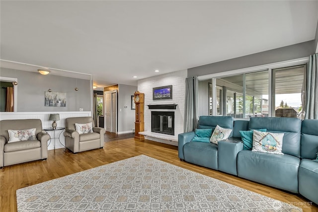 living area featuring a brick fireplace, recessed lighting, and wood finished floors