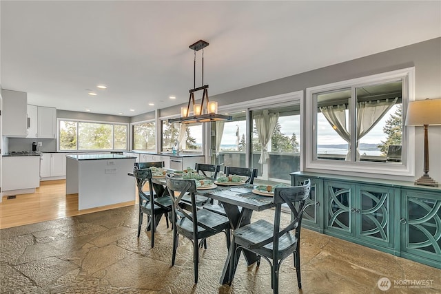 dining area with stone tile floors, recessed lighting, and a chandelier