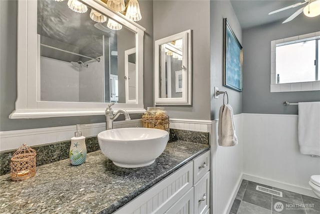 bathroom with ceiling fan, vanity, toilet, baseboards, and visible vents