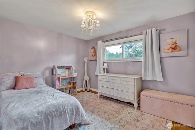 bedroom featuring baseboards, wood finished floors, and a chandelier