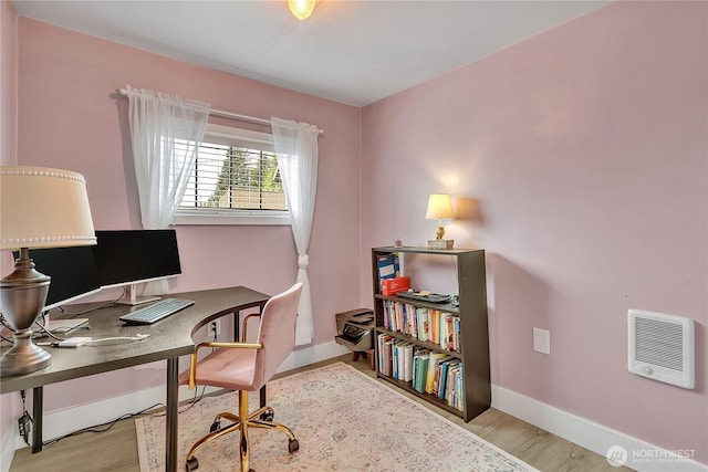 office space featuring baseboards, heating unit, and wood finished floors