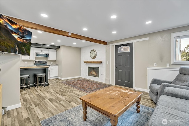 living area featuring recessed lighting, baseboards, a fireplace, and light wood finished floors