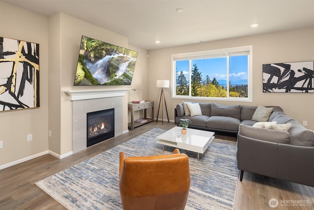 living area with baseboards, a tile fireplace, wood finished floors, and recessed lighting