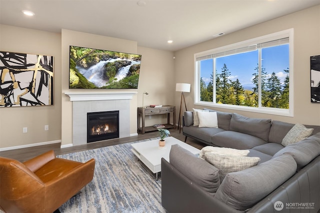 living room featuring visible vents, baseboards, recessed lighting, wood finished floors, and a tile fireplace