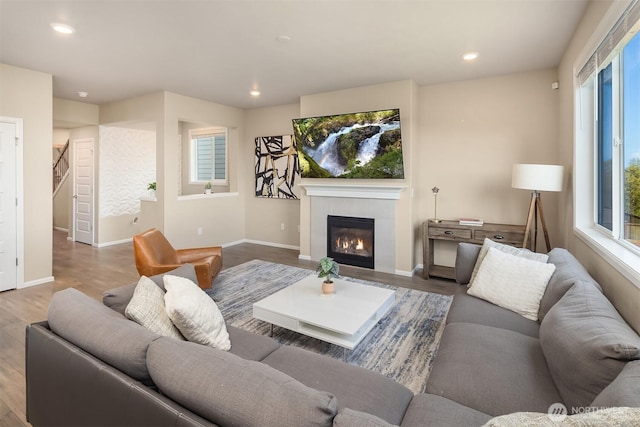 living area with recessed lighting, a healthy amount of sunlight, wood finished floors, and a fireplace