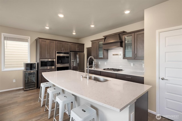 kitchen featuring a breakfast bar, dark brown cabinetry, premium range hood, baseboards, and appliances with stainless steel finishes