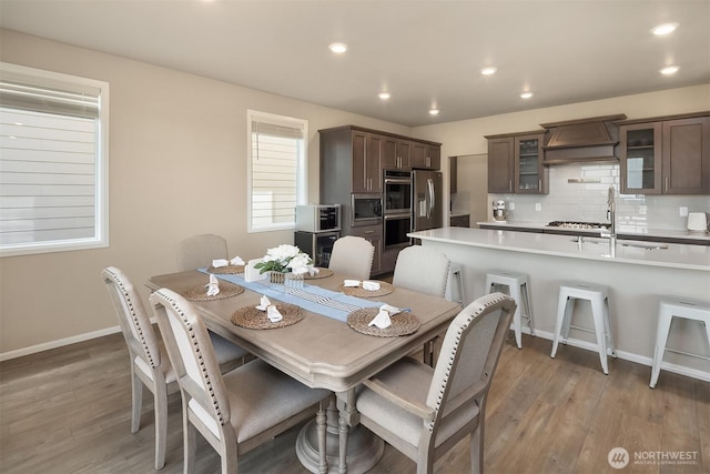 dining room featuring baseboards, light wood finished floors, and recessed lighting