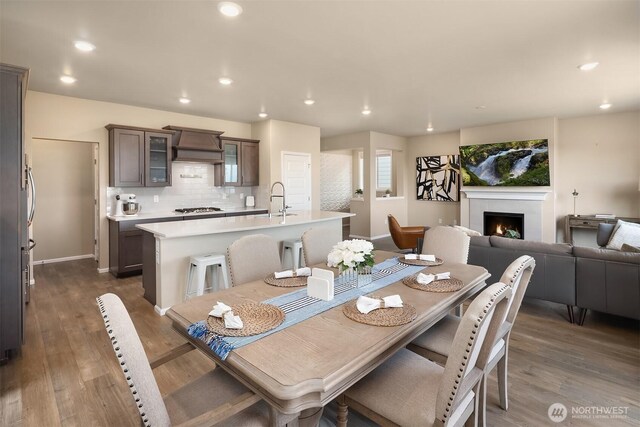 dining space featuring recessed lighting, baseboards, dark wood-style floors, and a lit fireplace
