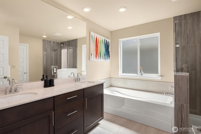 bathroom featuring a garden tub, a sink, and tiled shower
