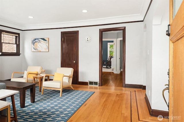 living area with recessed lighting, baseboards, wood finished floors, visible vents, and ornamental molding