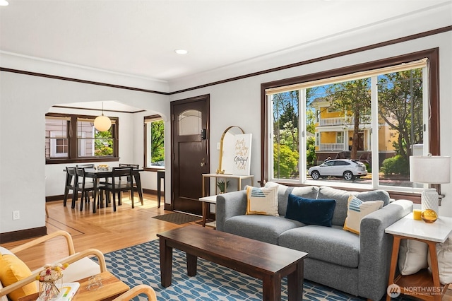 living area with crown molding, arched walkways, recessed lighting, baseboards, and wood finished floors