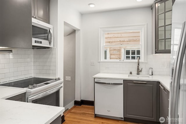kitchen featuring light wood-style floors, a sink, tasteful backsplash, and stainless steel appliances