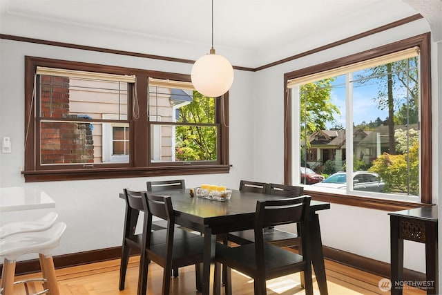 dining room with baseboards, ornamental molding, and wood finished floors
