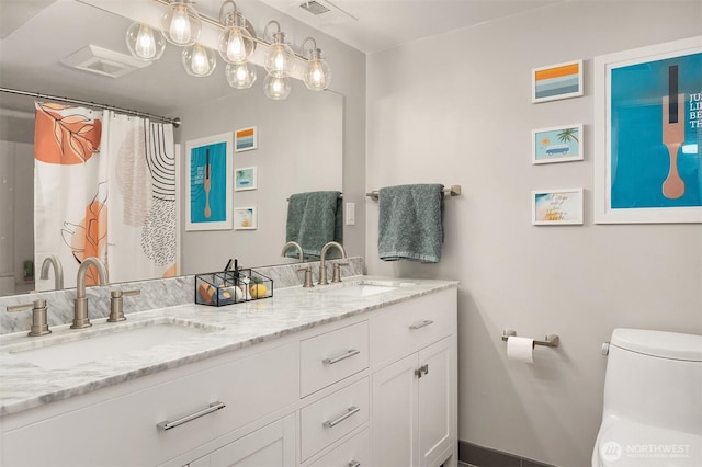 full bathroom with double vanity, toilet, visible vents, and a sink