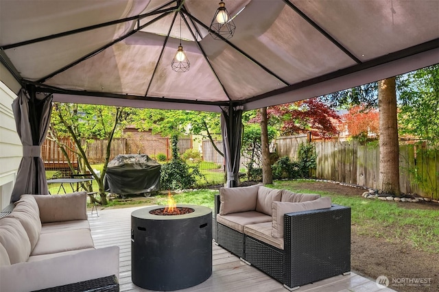 wooden deck featuring a gazebo, a fenced backyard, a grill, and an outdoor living space with a fire pit