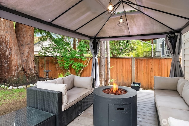 wooden deck with a gazebo, a fenced backyard, and an outdoor living space with a fire pit