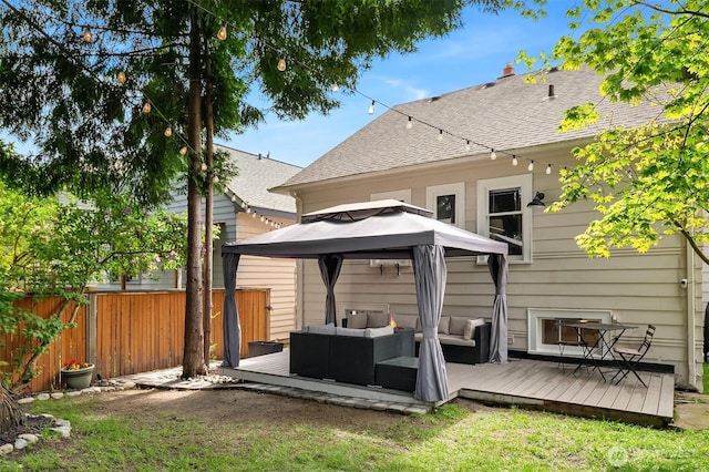 back of property featuring a wooden deck, fence, roof with shingles, an outdoor hangout area, and a gazebo