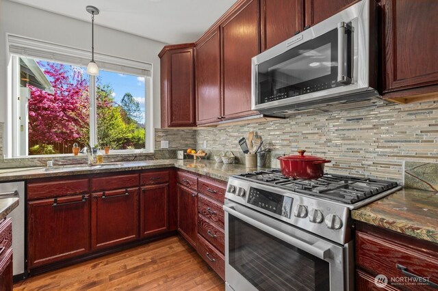 kitchen with backsplash, appliances with stainless steel finishes, a sink, and light wood-style flooring