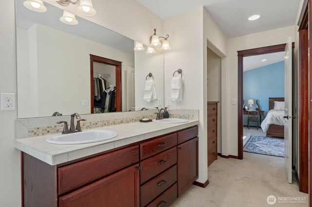 ensuite bathroom featuring double vanity, a sink, a walk in closet, and ensuite bath