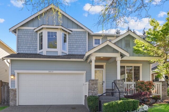 craftsman-style house with covered porch, board and batten siding, driveway, a garage, and stone siding