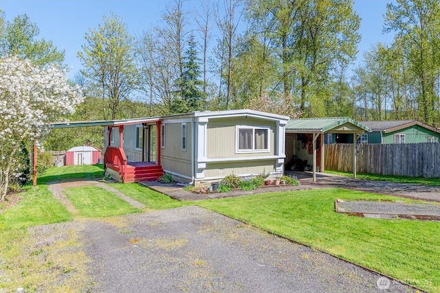 157 Camelot Dr, Castle Rock, WA 98611 - manufactured / mobile home with an outdoor structure, fence, a storage unit, a front lawn, and driveway