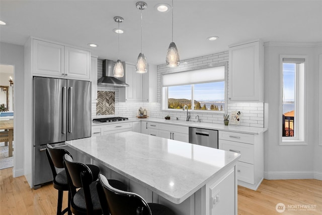 kitchen with stainless steel appliances, wall chimney exhaust hood, a sink, baseboards, and recessed lighting
