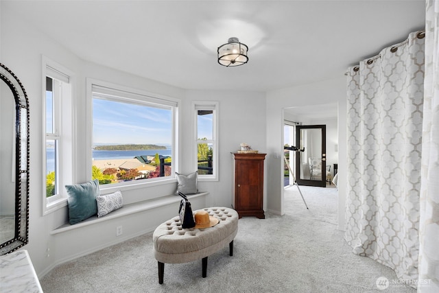 sitting room with carpet floors, a water view, and baseboards