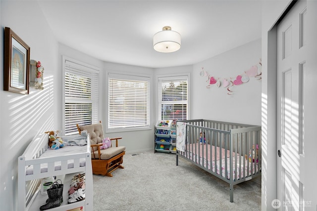 carpeted bedroom featuring a nursery area and baseboards