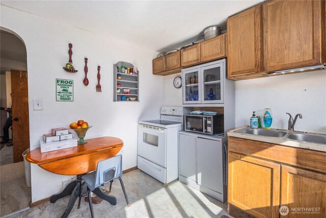 15721 67th Ave NE, Arlington, WA 98223 - kitchen with white range with electric stovetop, arched walkways, a sink, brown cabinetry, and stainless steel microwave