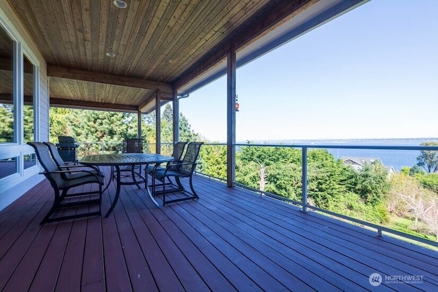 wooden terrace with outdoor dining area and a water view