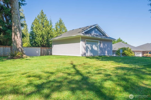 rear view of house featuring a lawn, a garage, and fence