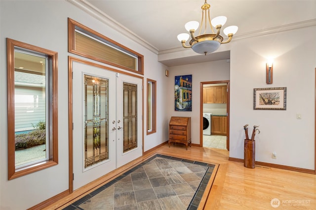 entrance foyer with an inviting chandelier, french doors, wood finished floors, baseboards, and washer / clothes dryer