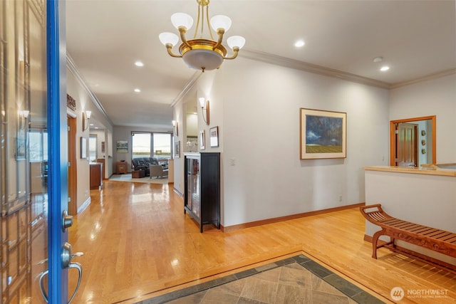 hall featuring wood finished floors, a notable chandelier, crown molding, baseboards, and recessed lighting