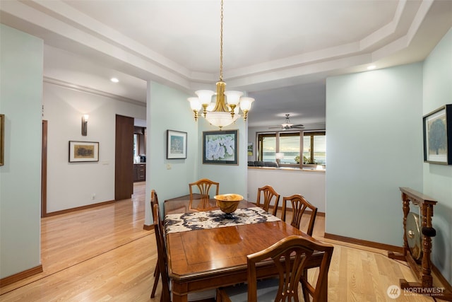 dining space with recessed lighting, baseboards, an inviting chandelier, a raised ceiling, and light wood-type flooring