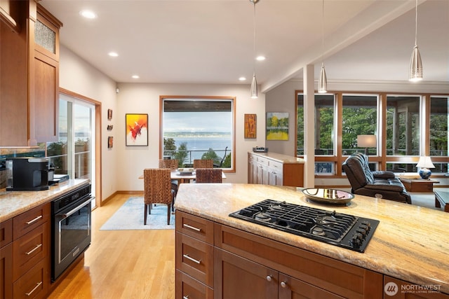 kitchen with light wood-type flooring, black appliances, light stone counters, and recessed lighting