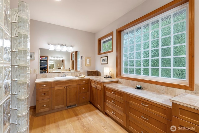 bathroom with walk in shower, vanity, visible vents, and wood finished floors