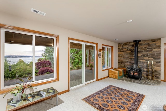 doorway featuring baseboards, a wood stove, visible vents, and carpet floors