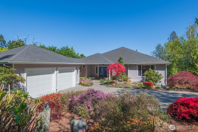 ranch-style home with an attached garage, a shingled roof, and driveway