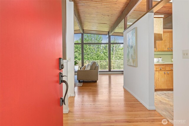 hall with expansive windows, light wood-style flooring, baseboards, beam ceiling, and wood ceiling