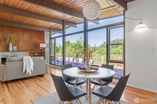 dining space with expansive windows, beamed ceiling, wooden ceiling, and light wood-type flooring