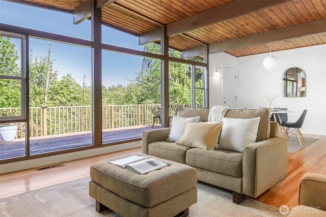 living area featuring beamed ceiling, wood finished floors, and wooden ceiling