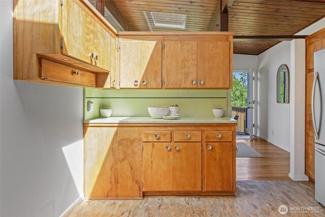 kitchen featuring tile countertops, wood ceiling, baseboards, light wood-style flooring, and freestanding refrigerator