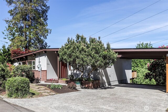 mid-century modern home featuring asphalt driveway and a carport