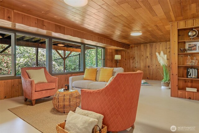 sitting room with wooden walls, wooden ceiling, and finished concrete flooring