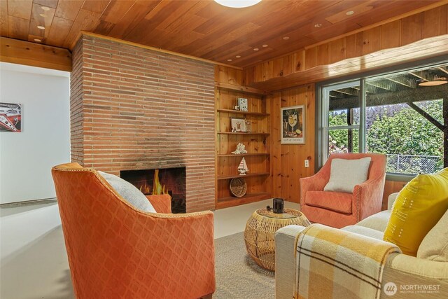 carpeted living area featuring wooden ceiling, a brick fireplace, built in features, and wood walls
