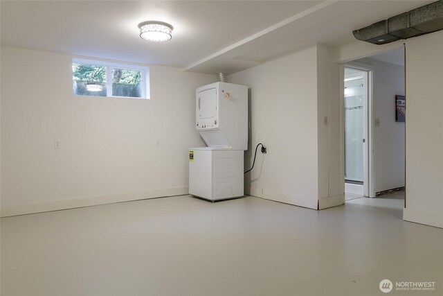 basement with stacked washing machine and dryer and baseboards